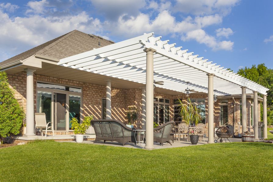 Bílá zahradní pergola u stěny cihlového rodinného domu